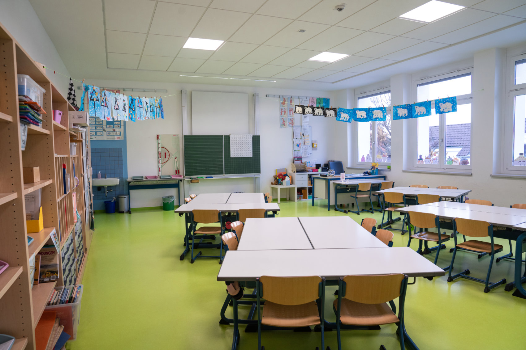 Blick in leeres Klassenzimmer mit Wasserfarbenbildern an Wäscheleinen 1