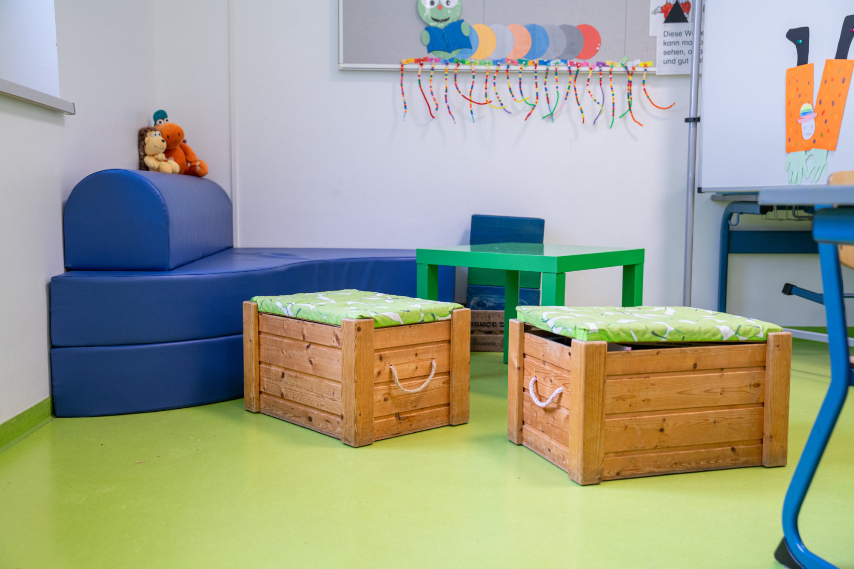 Chillecke mit blauem Ecksofa und zwei Holzkisten als Hocker Chillecke mit blauem Ecksofa und zwei Holzkisten als Hocker