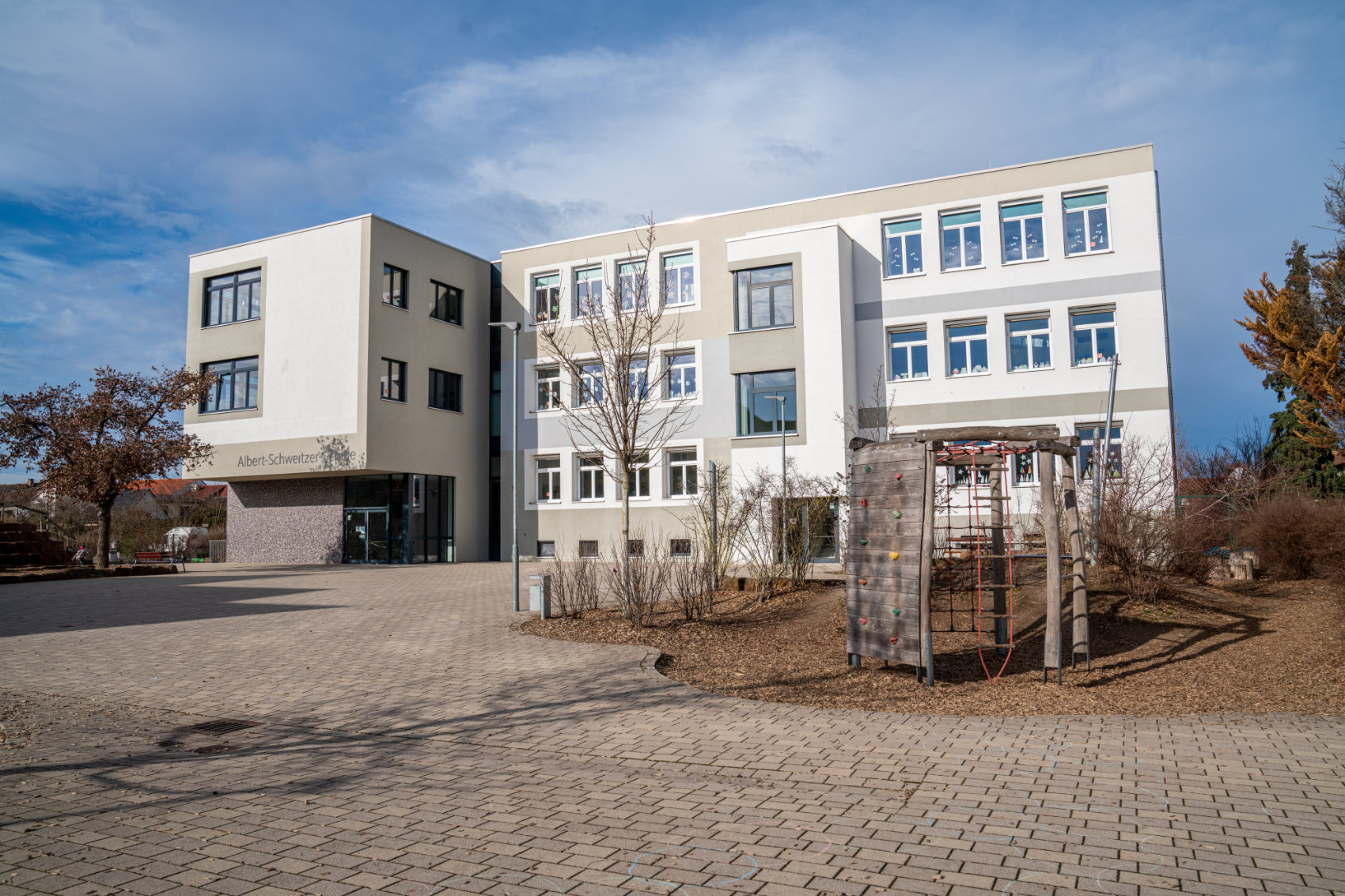 Das Schulgebäude von rechts vorne mit Klettergerüst davor Das Schulgebäude von rechts vorne mit Klettergerüst davor