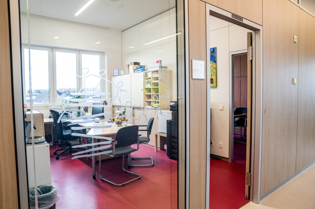 Das Sekretariatsbüro gesehen durch eine Glaswand mit dem Logo der Schule Das Sekretariatsbüro gesehen durch eine Glaswand mit dem Logo der Schule