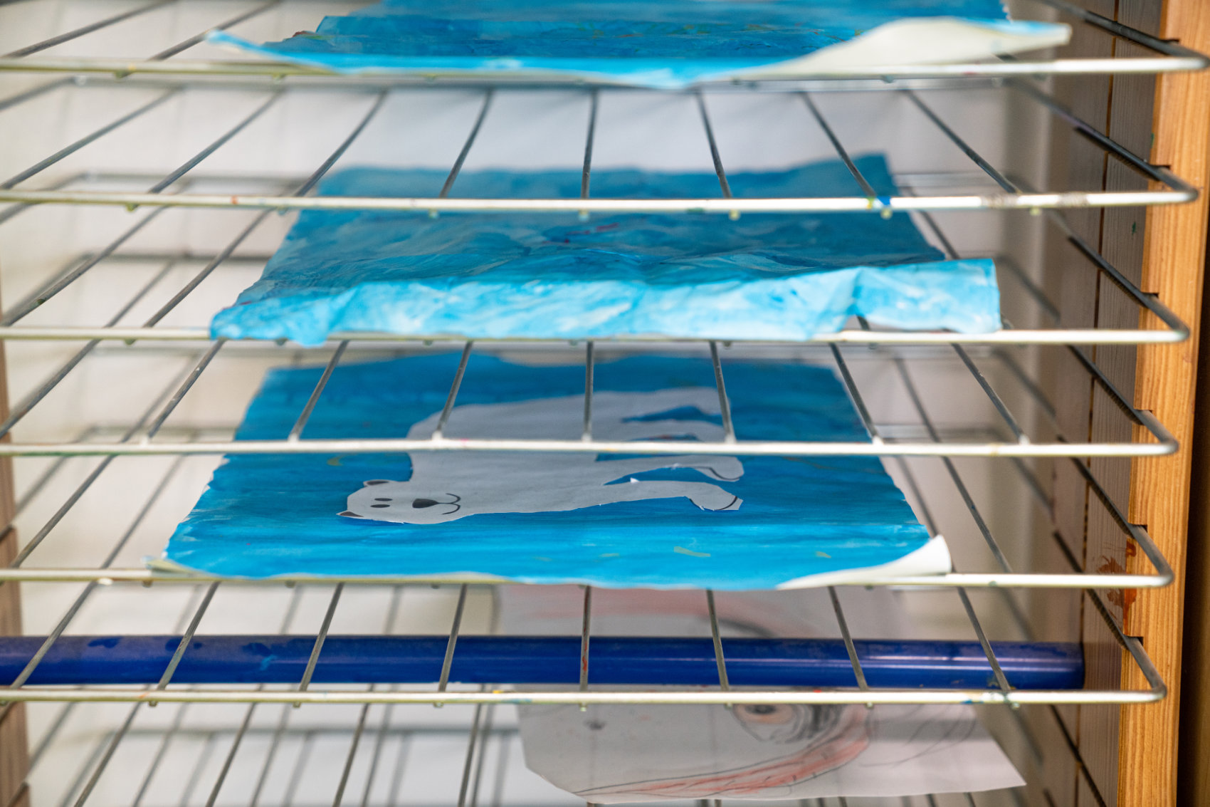 Regal mit Gitterrosten und zum Trocknen eingelegten Wasserfarbenbildern Regal mit Gitterrosten und zum Trocknen eingelegten Wasserfarbenbildern