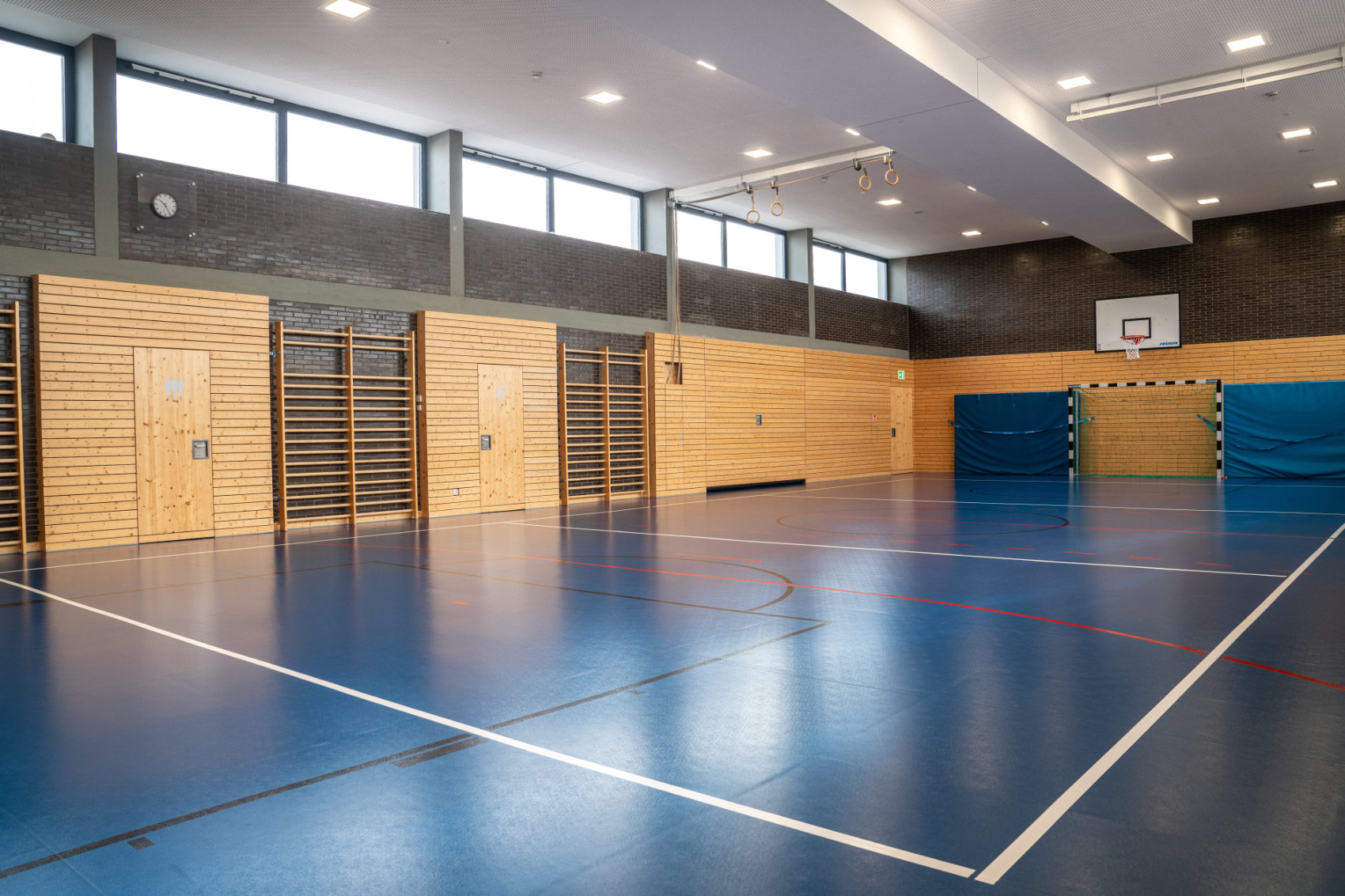 Sporthalle mit blauem Boden und holzverkleideten Wänden 2 Sporthalle mit blauem Boden und holzverkleideten Wänden 2